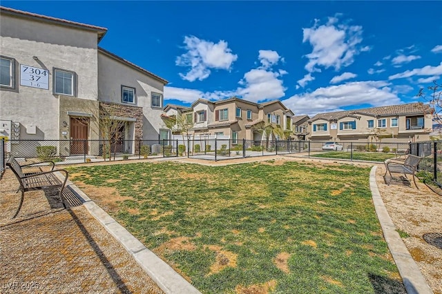 view of property's community featuring a residential view, a lawn, and fence