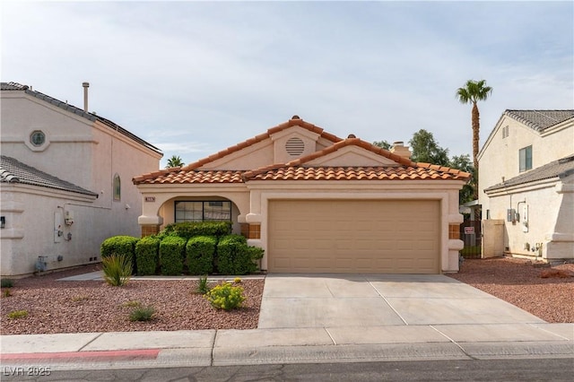 mediterranean / spanish-style house featuring concrete driveway, an attached garage, a tiled roof, and stucco siding