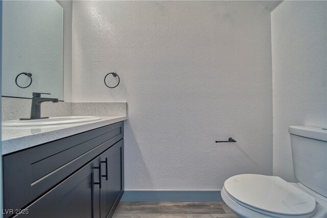 384 E Erin St Unit 3, Pahrump, NV 89048 - half bathroom featuring a textured wall, toilet, vanity, wood finished floors, and baseboards