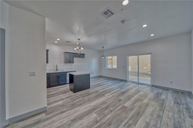 384 E Erin St Unit 3, Pahrump, NV 89048 - kitchen with light wood-style flooring, a kitchen island, a sink, baseboards, and light countertops