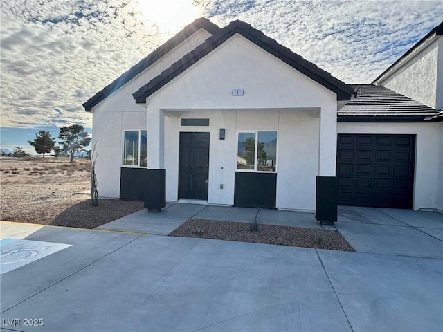 view of front of property featuring driveway, an attached garage, and stucco siding