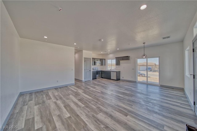 unfurnished living room with recessed lighting, a sink, visible vents, baseboards, and light wood finished floors