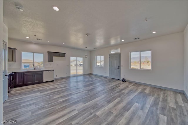 unfurnished living room featuring light wood-type flooring, a healthy amount of sunlight, baseboards, and recessed lighting