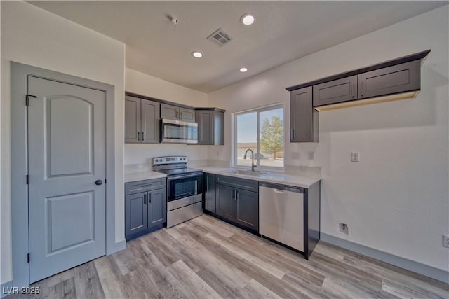 kitchen featuring visible vents, stainless steel appliances, a sink, and light countertops