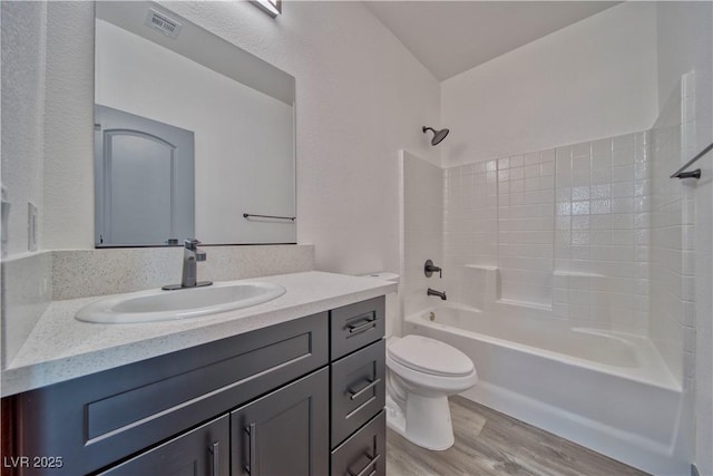 full bath featuring visible vents, toilet, tub / shower combination, vanity, and wood finished floors