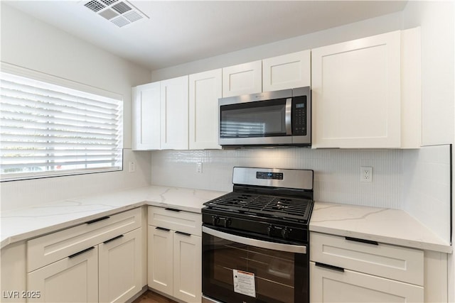 kitchen featuring appliances with stainless steel finishes, visible vents, backsplash, and white cabinetry