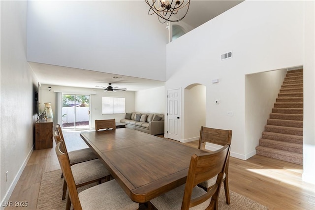 dining area with light wood finished floors, stairs, visible vents, and arched walkways