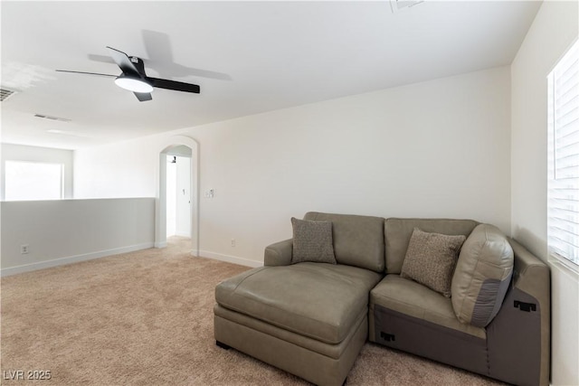 living room with baseboards, visible vents, arched walkways, a ceiling fan, and light colored carpet