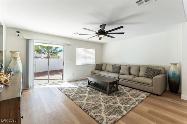 living area with ceiling fan, wood finished floors, visible vents, and baseboards