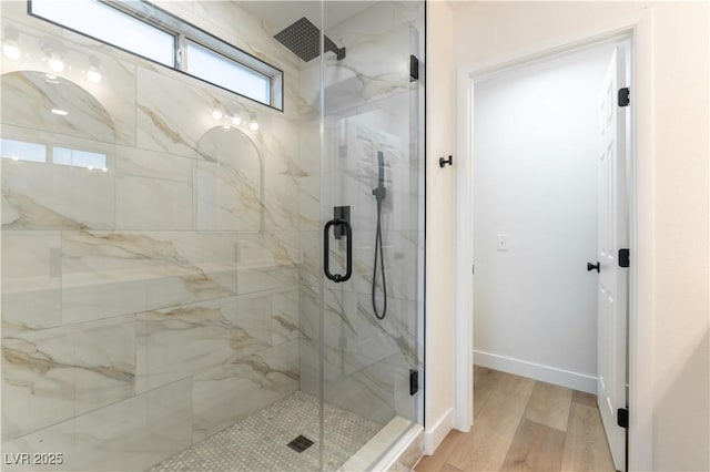 bathroom featuring a marble finish shower, baseboards, and wood finished floors