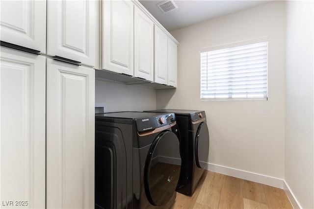 laundry room with visible vents, baseboards, light wood-style floors, cabinet space, and washer and clothes dryer