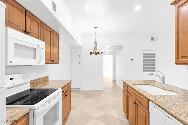 kitchen featuring white appliances, brown cabinetry, visible vents, and a sink