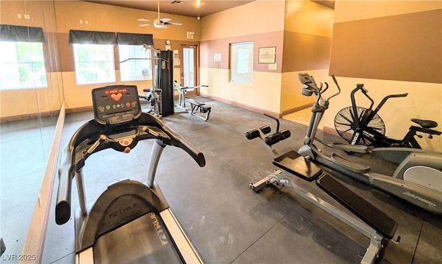 gym with a ceiling fan and baseboards