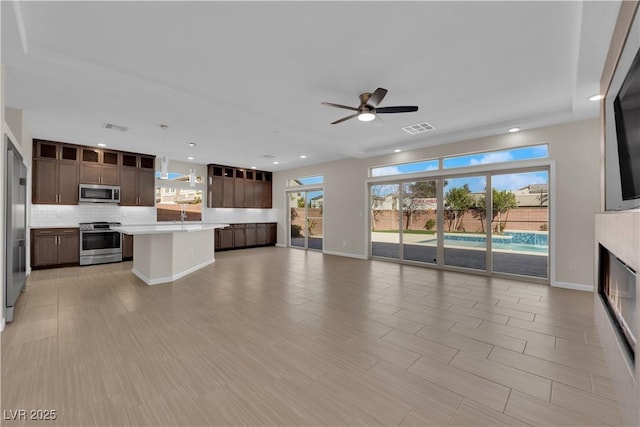 unfurnished living room with baseboards, visible vents, a ceiling fan, and recessed lighting