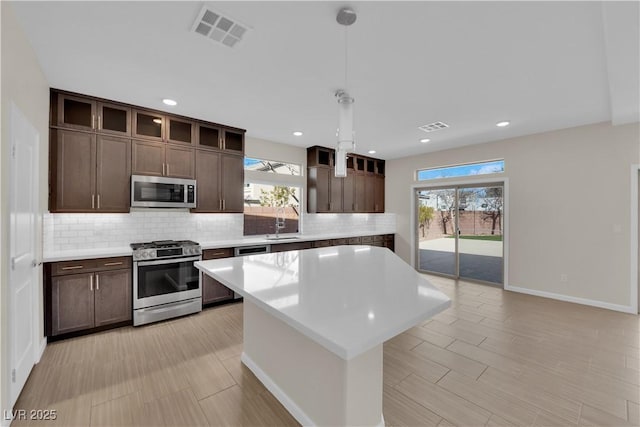 kitchen with appliances with stainless steel finishes, light countertops, visible vents, and backsplash