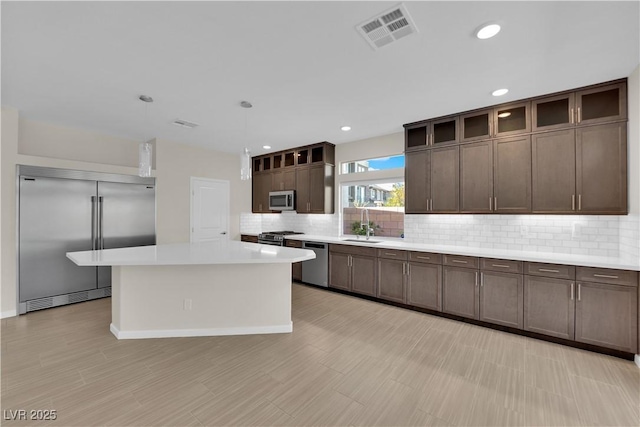 kitchen with stainless steel appliances, light countertops, visible vents, and dark brown cabinetry