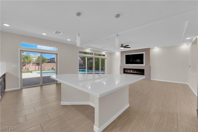 kitchen featuring light countertops, a glass covered fireplace, visible vents, and recessed lighting