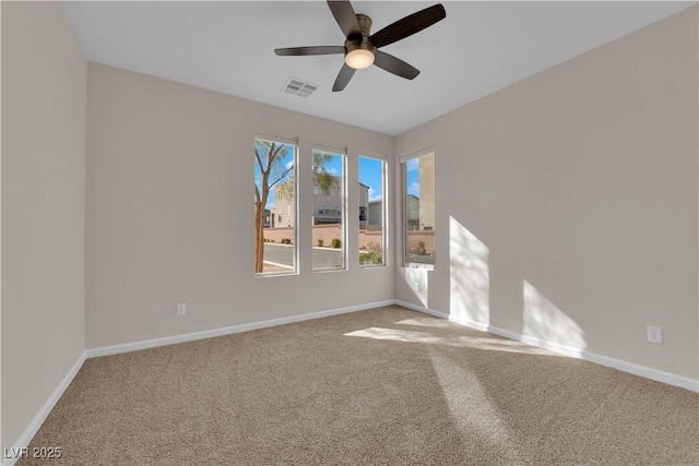 carpeted empty room with visible vents, ceiling fan, and baseboards