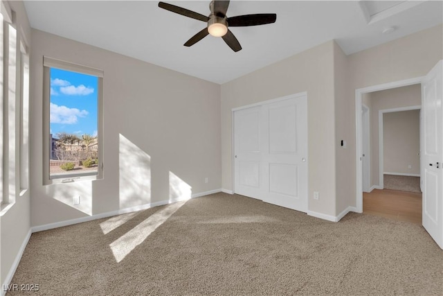 unfurnished bedroom featuring carpet floors, a closet, baseboards, and a ceiling fan