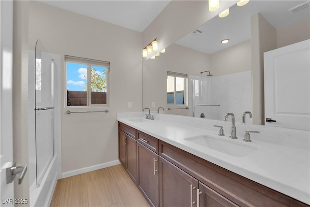 bathroom featuring plenty of natural light, visible vents, a sink, and baseboards