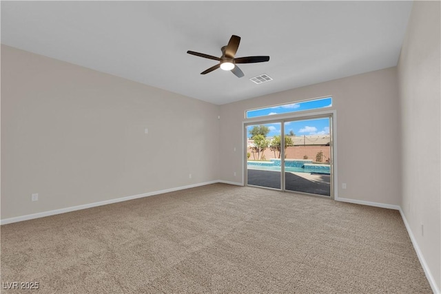 carpeted spare room with baseboards, visible vents, and a ceiling fan