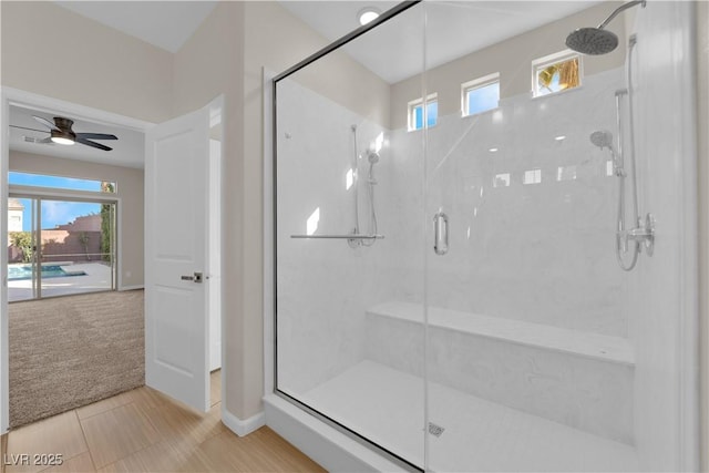 bathroom featuring ceiling fan and a shower stall