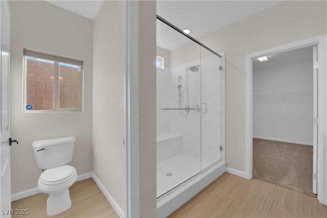 bathroom with baseboards, a shower stall, toilet, and wood finished floors