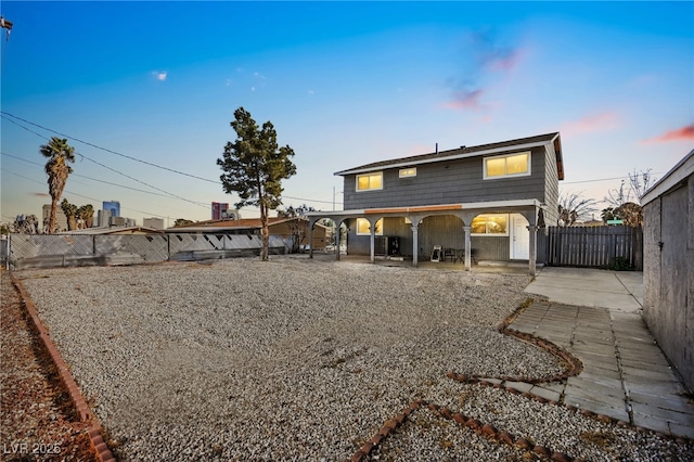 back of house at dusk featuring a fenced backyard and a patio