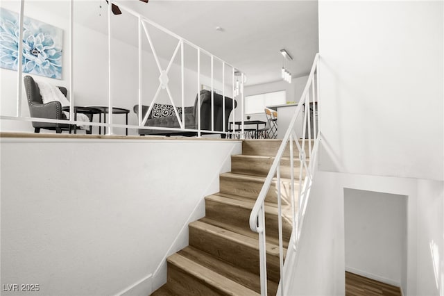 stairway with ceiling fan and wood finished floors