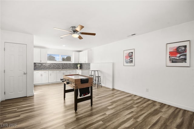 recreation room featuring a ceiling fan, baseboards, visible vents, and wood finished floors