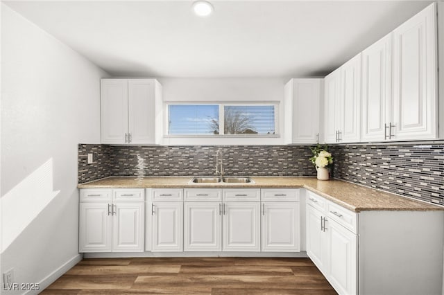 kitchen featuring tasteful backsplash, white cabinets, a sink, and wood finished floors