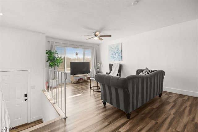 living area featuring ceiling fan, stairway, wood finished floors, and baseboards