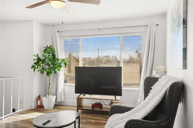 living area with ceiling fan, baseboards, and wood finished floors