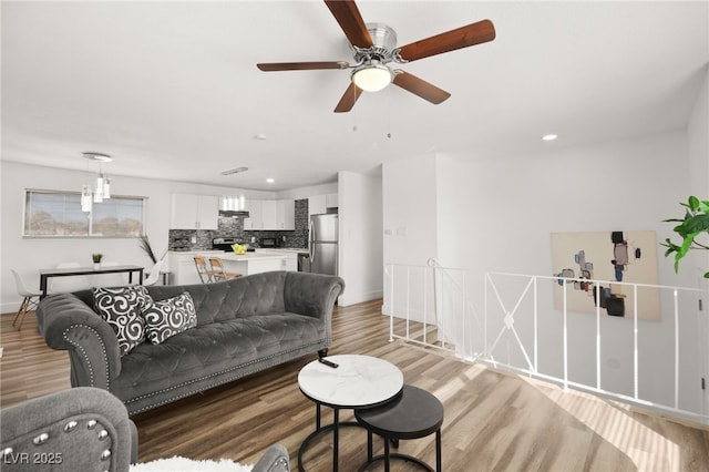 living room featuring light wood-type flooring, baseboards, and recessed lighting