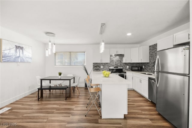 kitchen featuring decorative backsplash, stainless steel appliances, light countertops, and wood finished floors