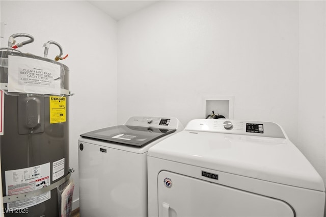 clothes washing area featuring washing machine and dryer, strapped water heater, and laundry area