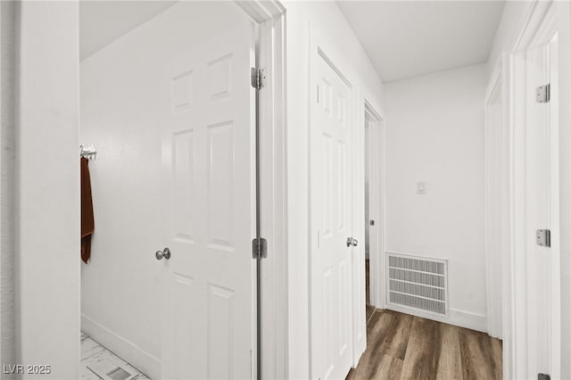 hall featuring baseboards, visible vents, and wood finished floors