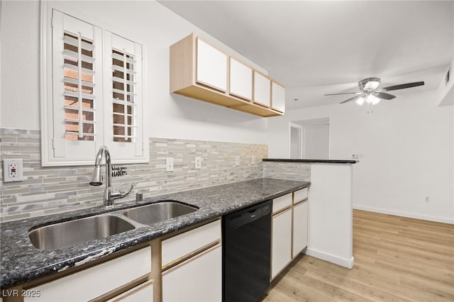 kitchen with a sink, light wood-type flooring, decorative backsplash, dishwasher, and dark stone countertops