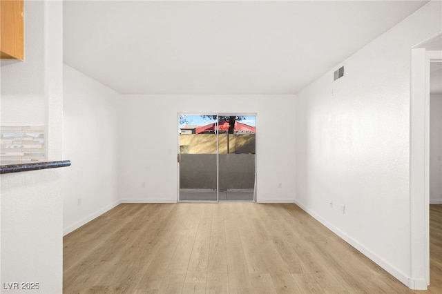 unfurnished room featuring wood finished floors, visible vents, and baseboards