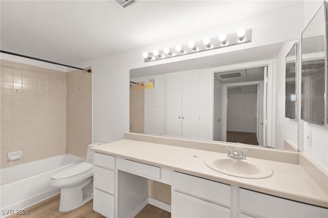 full bathroom featuring visible vents, toilet, wood finished floors, tub / shower combination, and vanity