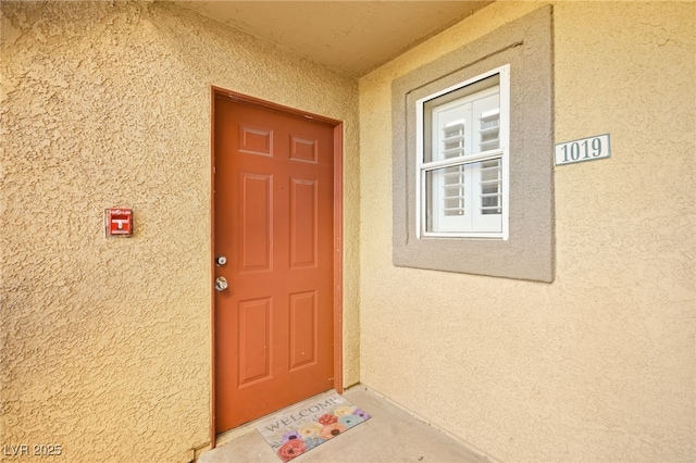 doorway to property featuring stucco siding