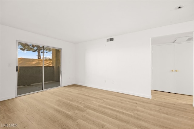 empty room featuring light wood-type flooring, visible vents, and baseboards