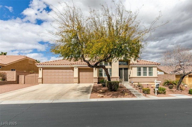 mediterranean / spanish-style home featuring fence, a garage, driveway, and stucco siding