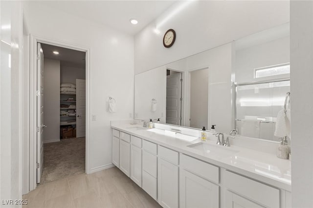 full bathroom featuring double vanity, an enclosed shower, a walk in closet, and a sink