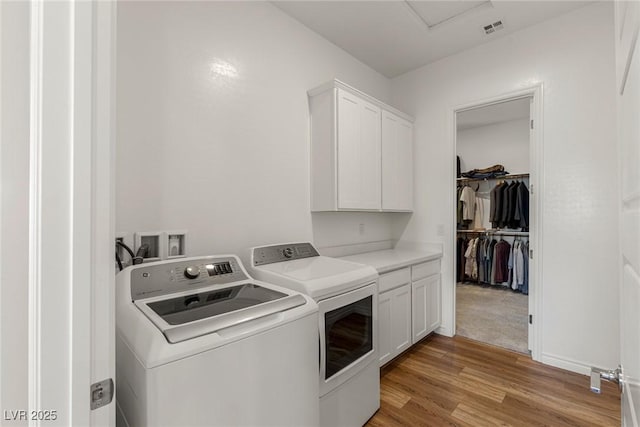 clothes washing area featuring cabinet space, visible vents, light wood finished floors, and separate washer and dryer