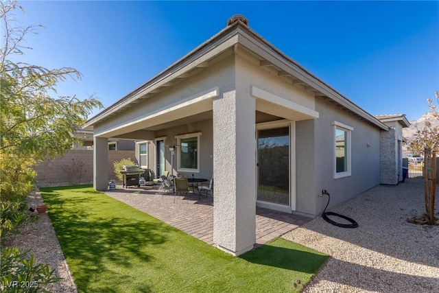 rear view of house featuring a patio area, fence, a lawn, and stucco siding