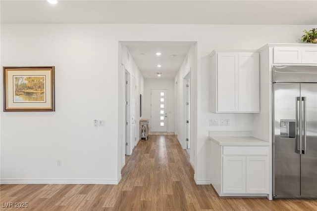 hall featuring light wood-style flooring, baseboards, and recessed lighting