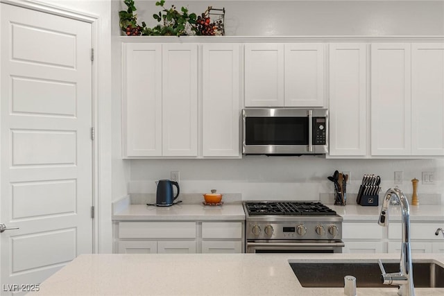 kitchen with appliances with stainless steel finishes, white cabinets, and a sink