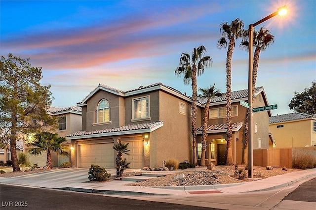 view of front of house featuring stucco siding, concrete driveway, fence, a garage, and a tiled roof