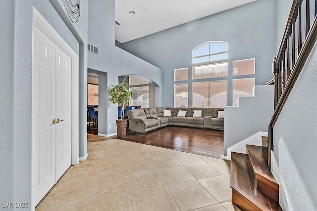 tiled living area with arched walkways, plenty of natural light, stairs, and visible vents